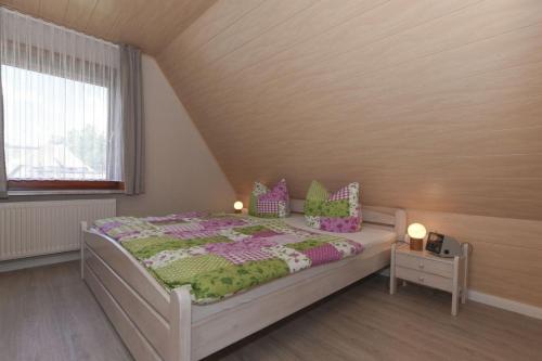 ニーブルムにあるGeestblick Whg 02 OG reのベッドルーム1室(紫と緑の枕が備わるベッド1台付)