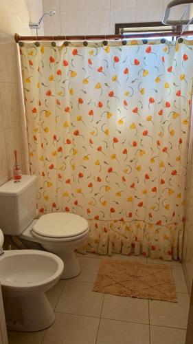 a bathroom with a shower curtain with a toilet at Lavanda 1 in El Calafate