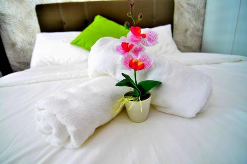 a pile of towels and a plant on a bed at Vivacity Jazz Suite New Luxury Vivacity Cozy Home LV8 in Kuching