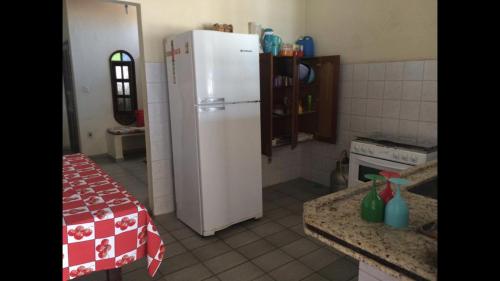 a kitchen with a white refrigerator and a table at Casa Temporada Frente à Praia Piscina Ar cond Nova Viçosa VA in Nova Viçosa