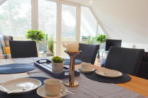 una mesa de comedor con platos y tazas y una vela en Hinter den Dünen D60, en Prerow