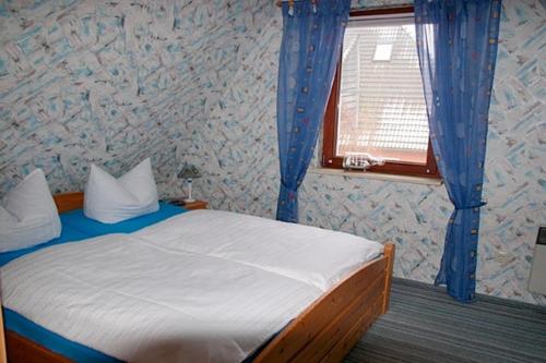 a bedroom with a bed with blue curtains and a window at Tabbert, Kerstin - 21697 in Zingst