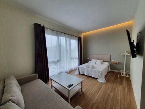 ein Wohnzimmer mit einer Couch und einem Bett in der Unterkunft REDONDELA APARTMENTS - Bedroom, Bathroom & Kitchen in Redondela
