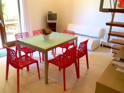 a table and red chairs in a living room at Case Fiorite in Riola Sardo