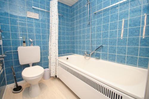 a blue tiled bathroom with a toilet and a bath tub at Berolina B 102 in Dahme