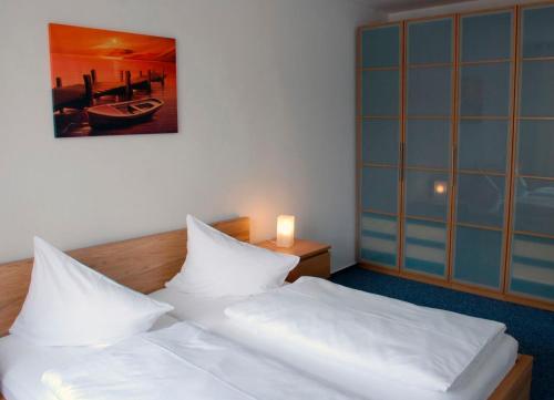 ein Schlafzimmer mit einem Bett mit weißer Bettwäsche und einer Lampe in der Unterkunft Zentrale Ferienwohnung 51qm im Hotel zur Börse in Hameln
