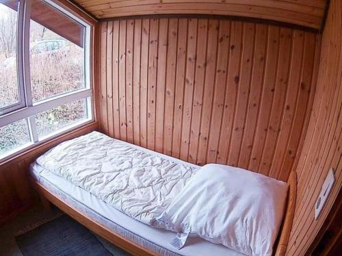 a small bed in a wooden room with a window at Ferienhaus Anke nur für Urlauber! in Bremke