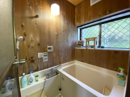 ein Bad mit einer Badewanne, einem Waschbecken und einem Fenster in der Unterkunft Mount Fuji Castle 2 in Yamanakako
