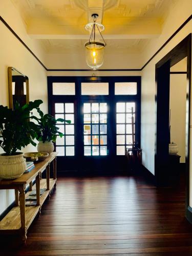 a room with a wooden floor and doors with plants at Ballina Manor Boutique Hotel in Ballina