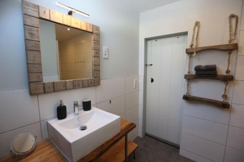 ein Badezimmer mit einem weißen Waschbecken und einem Spiegel in der Unterkunft BLUMENSTIL Ferienwohnungen 2 in Bad Salzungen