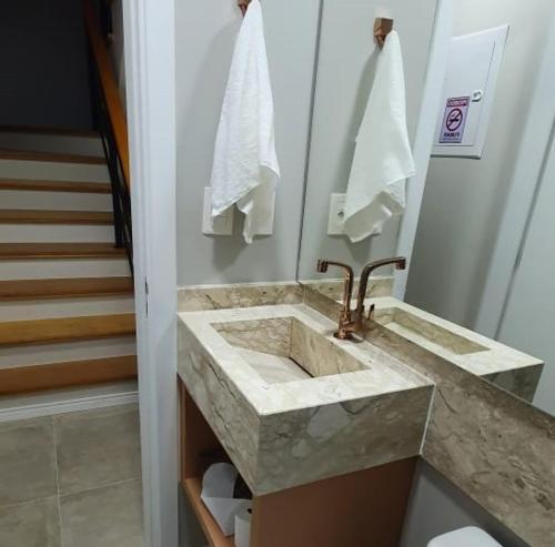 ein Badezimmer mit einem Marmorwaschbecken und einer Treppe in der Unterkunft Casa Nova Canela Condominio Fechado 40 in Canela