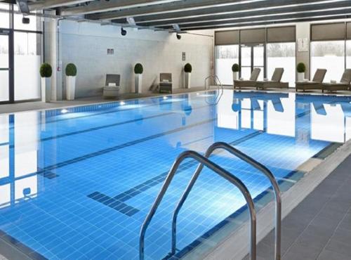 a large swimming pool with blue water in a building at Glasgow City Central Executive Triplex House, 3 Bedroom 3 Bathrooms 1 living room Kitchen - Huge Terrace for Master Bedroom - Private E Parking LEZ Congestion Zone Free - Garden - 5 mins drive to City Centre Central Station in Glasgow