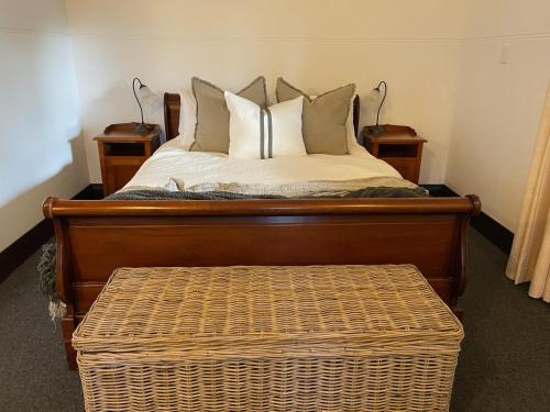 a bed with two nightstands and a wicker ottoman sidx sidx at Ballina Manor Boutique Hotel in Ballina