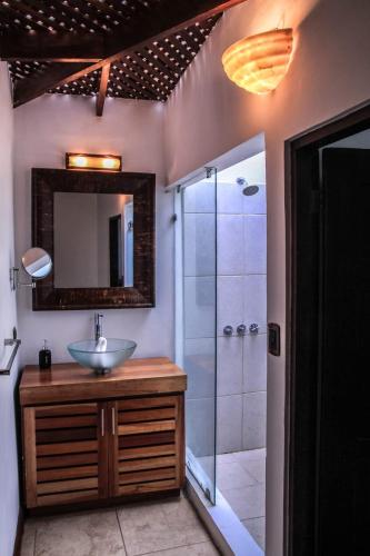 a bathroom with a sink and a shower with a mirror at Café de Playa Beach Front Hotel in Coco