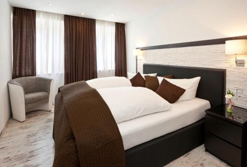 a bedroom with a large white bed and a chair at City Apart Hotel Füssen in Füssen