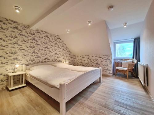a bedroom with a white bed in a room with floral wallpaper at MeerBlüte in Vadersdorf