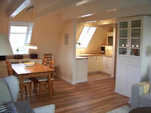 a kitchen and dining room with a table and chairs at Deichhof Whg 26 in Dunsum