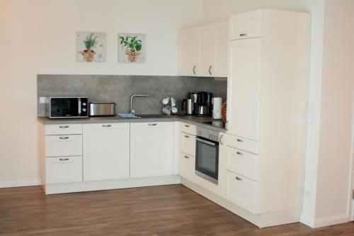 een witte keuken met witte kasten en een wastafel bij Ostsee - Appartement Nr 95 "Möwe" im Strand Resort in Heiligenhafen