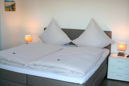 ハイリゲンハーフェンにあるOstsee - Appartement Nr 95 "Möwe" im Strand Resortのベッド(白いシーツ、枕付)