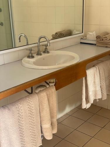 a bathroom with a sink and a mirror and towels at All Settlers Motor Inn Parkes in Parkes
