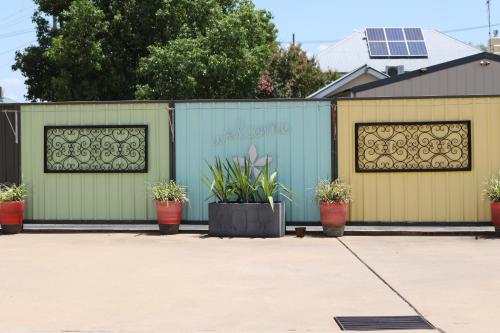 a fence with plants in pots in a driveway at All Settlers Motor Inn Parkes in Parkes