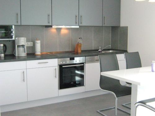une cuisine avec des placards blancs et une table et des chaises blanches dans l'établissement Ferienwohnungen Öker - Stadtvilla OG, à Grömitz