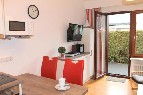 格洛米茨的住宿－"Wohnung 1 - G Pape" mit 2 Terrassen, kostenloses WLAN, Longstay Rabatt, Nähe Dünenpark，客厅配有桌子和2把红色椅子