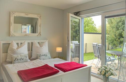 1 dormitorio con cama blanca y almohadas rojas en Ferienhaus Sewald, en Wulfen auf Fehmarn