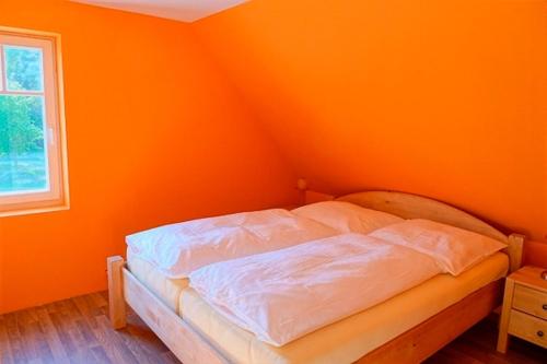 a bed in a room with an orange wall at Ferienhaushälfte Hanna in Wieck