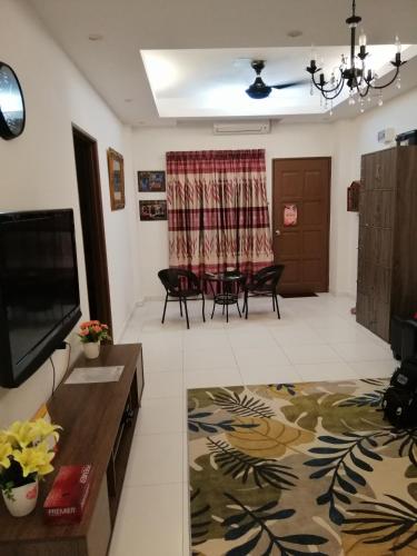 a living room with a television and a table and chairs at Onies Homestay Lumut Manjung in Lumut