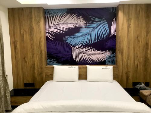 a bedroom with a bed with a painting on the wall at Meenakshi Inn in Udupi