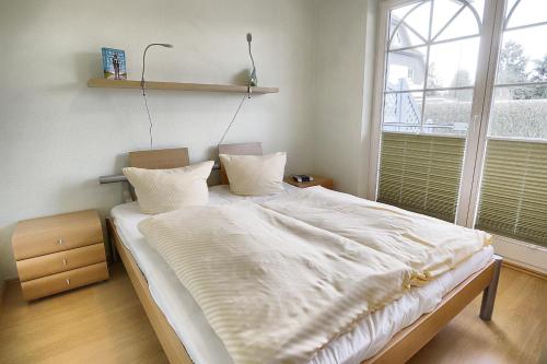 - une chambre avec un grand lit blanc et une fenêtre dans l'établissement Villa Vogelsang, FW 2, à Zingst