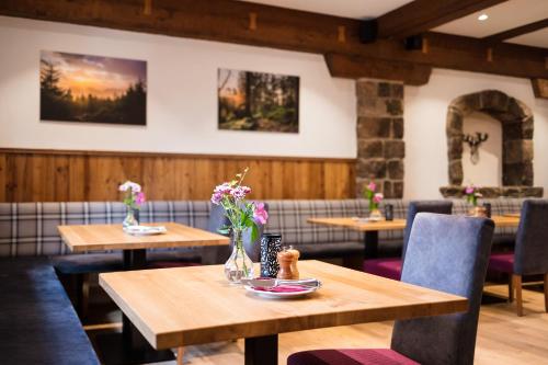 a restaurant with wooden tables and chairs and flowers at Hotel Spinnerhof in Sasbachwalden