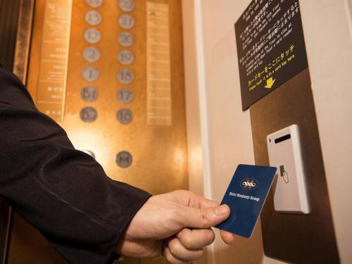 a man is holding a blue card in his hand at Hotel Monterey Edelhof Sapporo in Sapporo