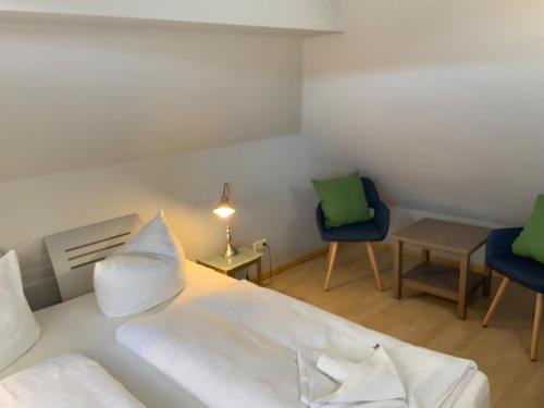 a bedroom with a white bed and two chairs at Fewo 4 Friedenstraße in Zingst