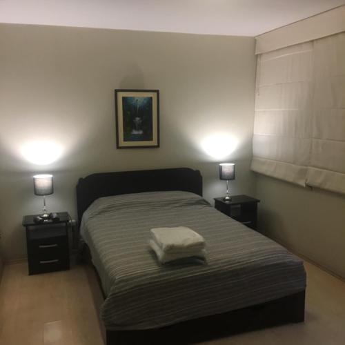 a bedroom with a bed with two night stands and two lamps at Host - San Isidro Sta Catalina in Lima