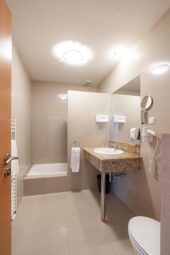 a bathroom with a sink and a toilet and a tub at Das Blaufränkisch Weinhotel & Restaurant in Girm