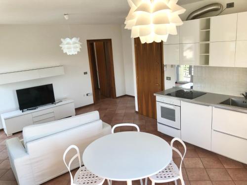 a white kitchen with a white table and chairs at Nevegal - Piccolo gioiello vicino al centro in Visome