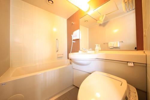 a bathroom with a toilet and a sink and a tub at Hotel Premium Green Hills in Sendai