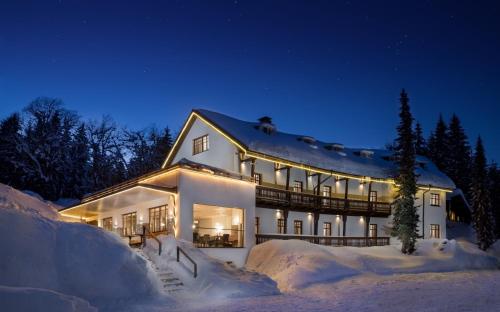 uma grande casa branca na neve à noite em Alpenhotel Bödele - Luxus Suite mit 2 SZ 21 em Schwarzenberg im Bregenzerwald