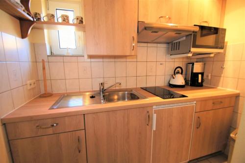 eine kleine Küche mit einer Spüle und einer Mikrowelle in der Unterkunft Rudow in Dahme