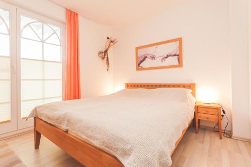 a white bedroom with a bed and a window at Fritz-Reuter-Straße 2 Whg 2 in Zingst
