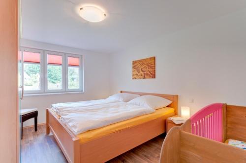 a bedroom with a bed and a desk and windows at Ferienhaushälfte Hanna in Wieck