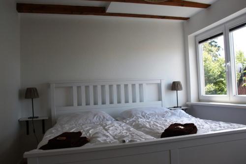 - une chambre dotée d'un lit blanc avec deux sacs dans l'établissement Reihenhaus - Seeschwalbe, à Neue Tiefe Fehmarn