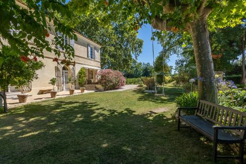 a park bench under a tree next to a house at Mas de Capelou in Avignon