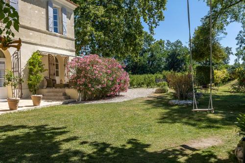a yard with a house with a swing and flowers at Mas de Capelou in Avignon