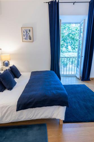 a bedroom with a bed with a blue blanket and a window at Mas de Capelou in Avignon