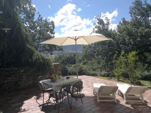 a table and chairs with an umbrella on a patio at Casale degli ulivi in Gualdo Tadino