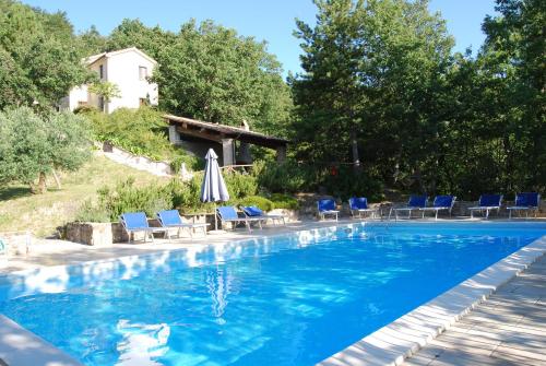 a swimming pool with chairs and an umbrella at Casale degli ulivi in Gualdo Tadino