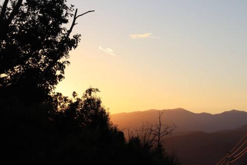 a sunset in the mountains with trees in the foreground at Chalet Village- Amazing Mountain Views - Piney Butt Place in Gatlinburg